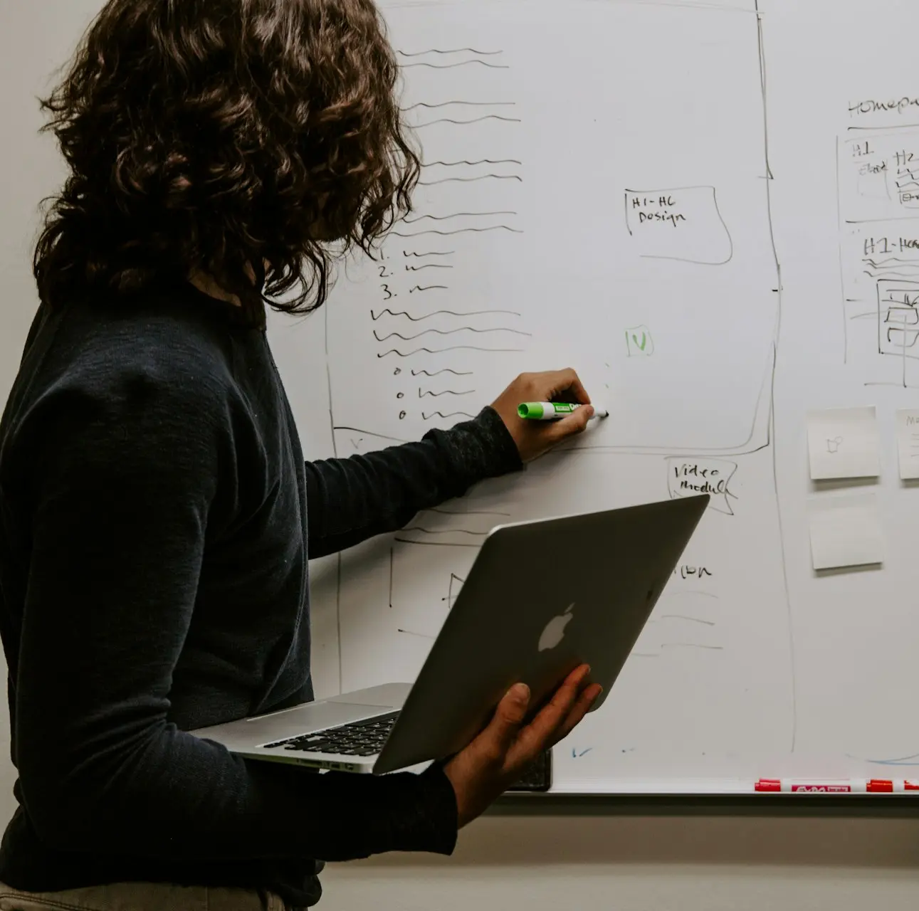 man wearing gray polo shirt beside dry-erase board
